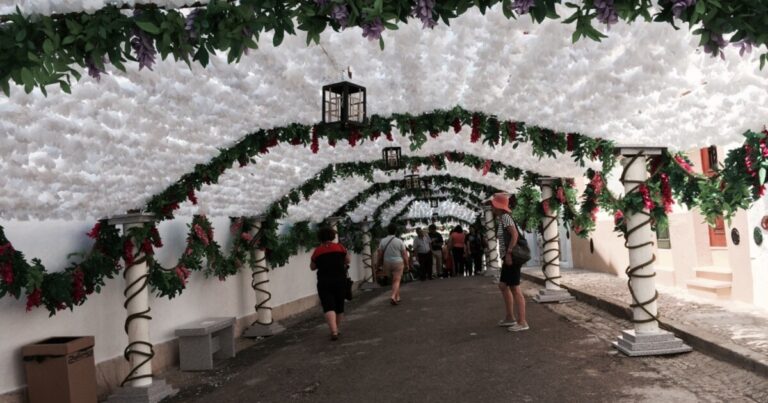 Bezoekers lopen door een straat in Campo Maior onder duizenden witte papieren bloemen.