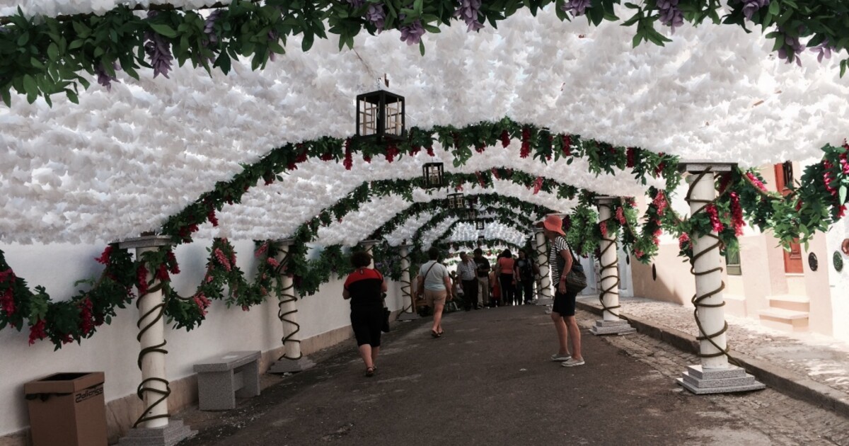Bezoekers lopen door een straat in Campo Maior onder duizenden witte papieren bloemen.